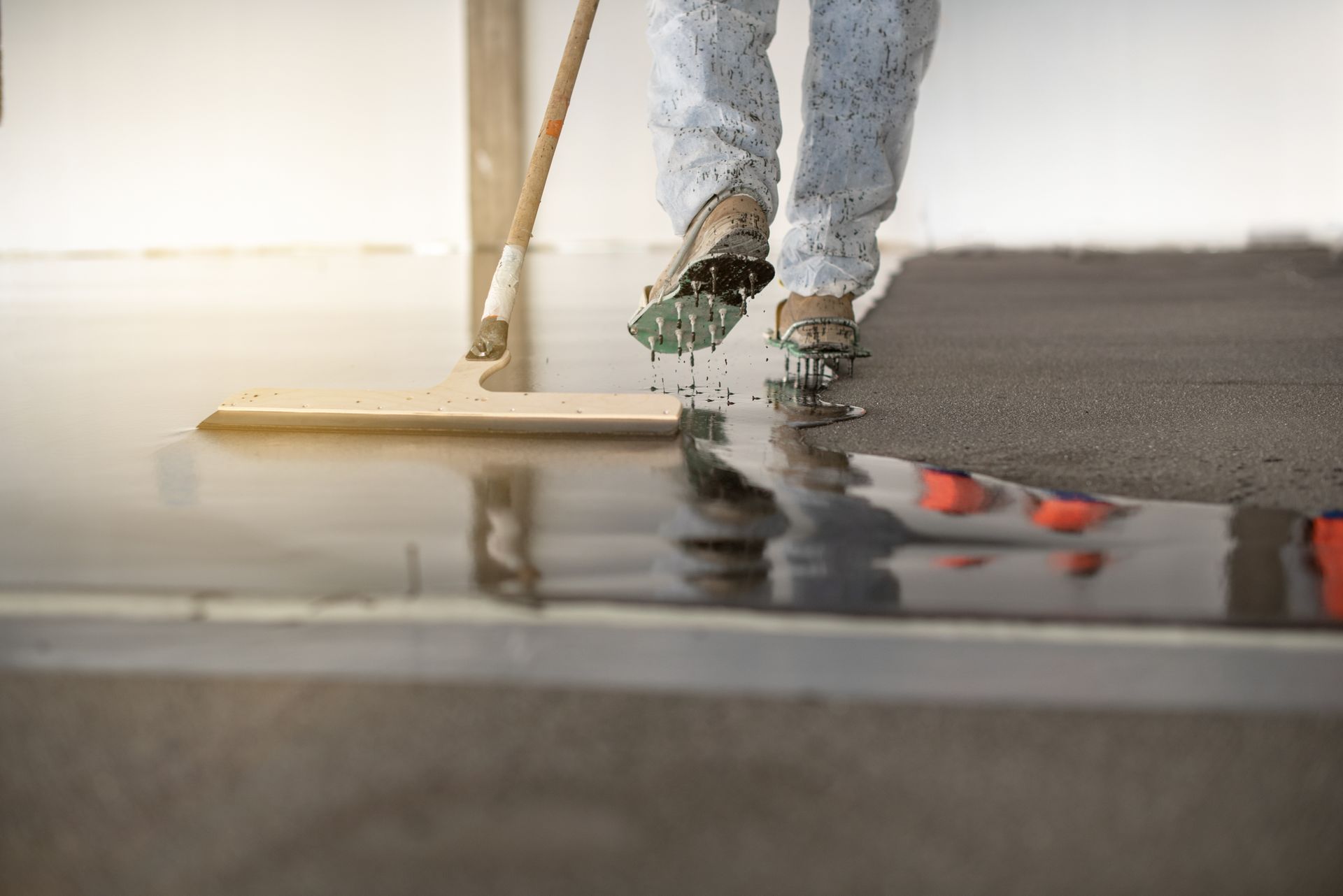 Person applying epoxy coating to a concrete floor with a squeegee.