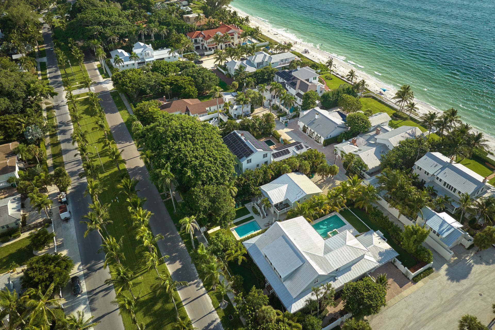 Aerial view of beachfront homes and street lined with trees, next to ocean. Aerial view of beachfront homes and street lined with trees, next to ocean.