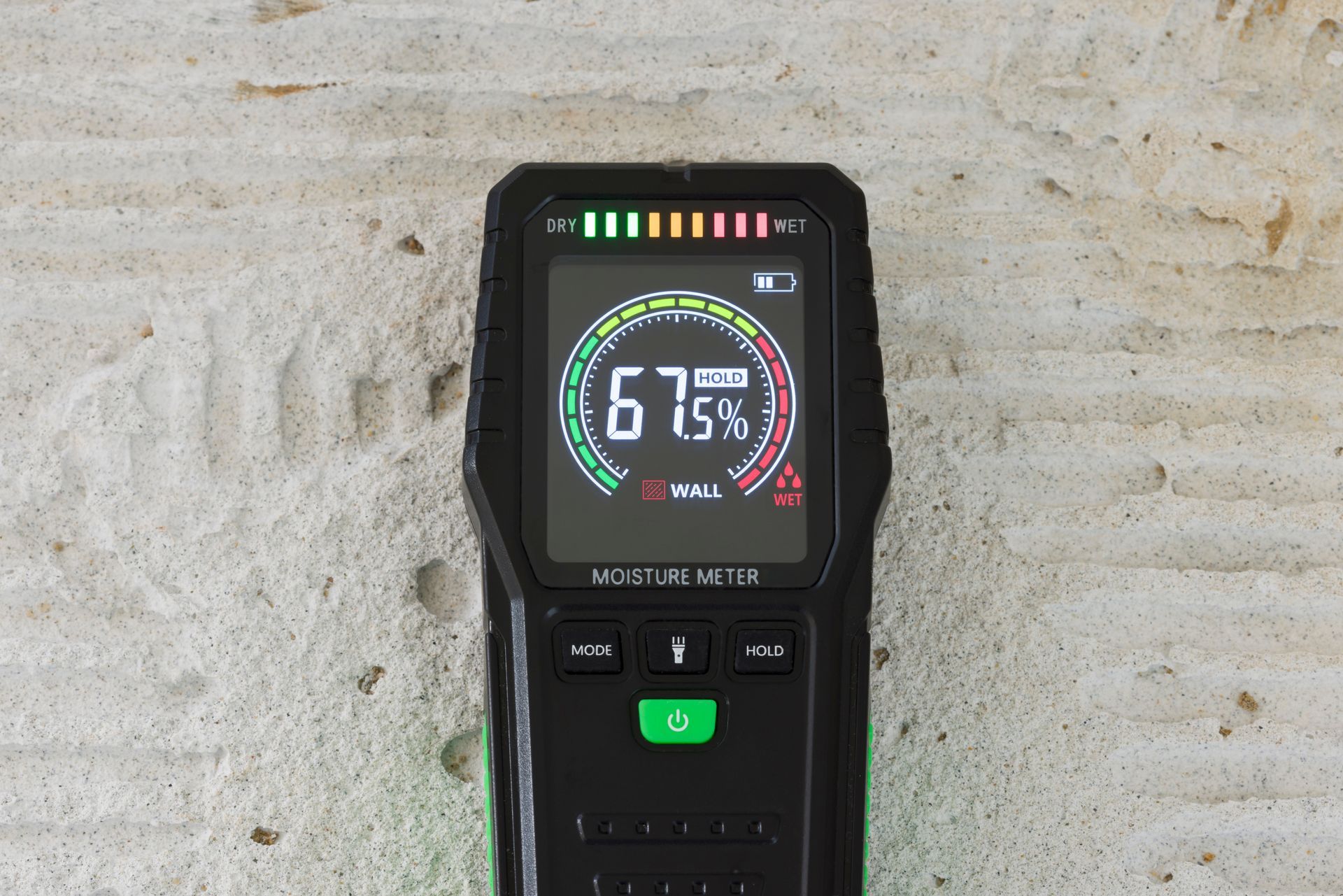 Moisture meter displaying 67%, green and red indicators, on a light-colored surface. Moisture meter displaying 67%, green and red indicators, on a light-colored surface.