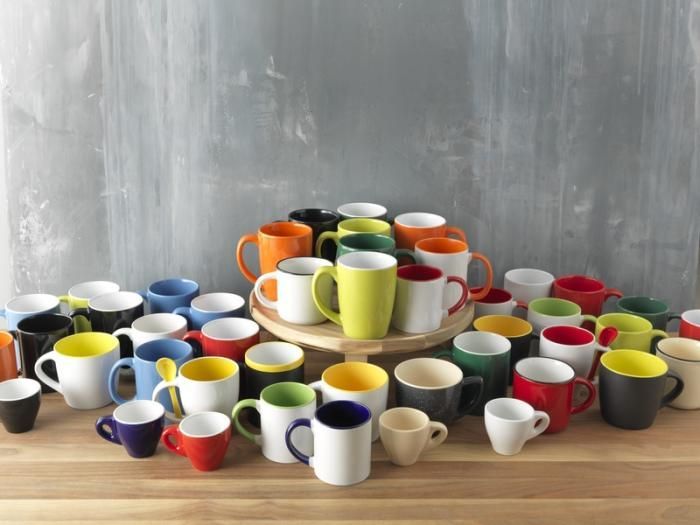 A table filled with many different colored coffee mugs