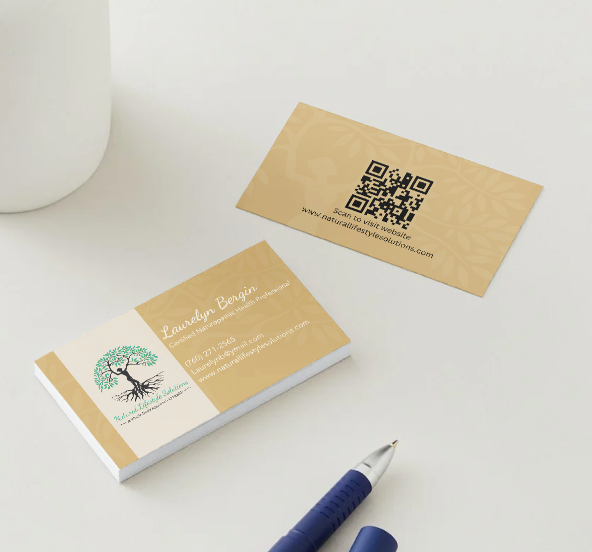 Business cards with tree logo and QR code. Pen and ceramic item on a white surface.