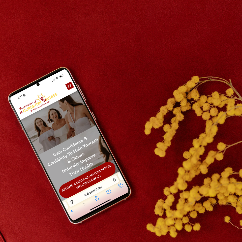 Smartphone displaying a website with three women. Yellow flowers lay nearby on a red surface.