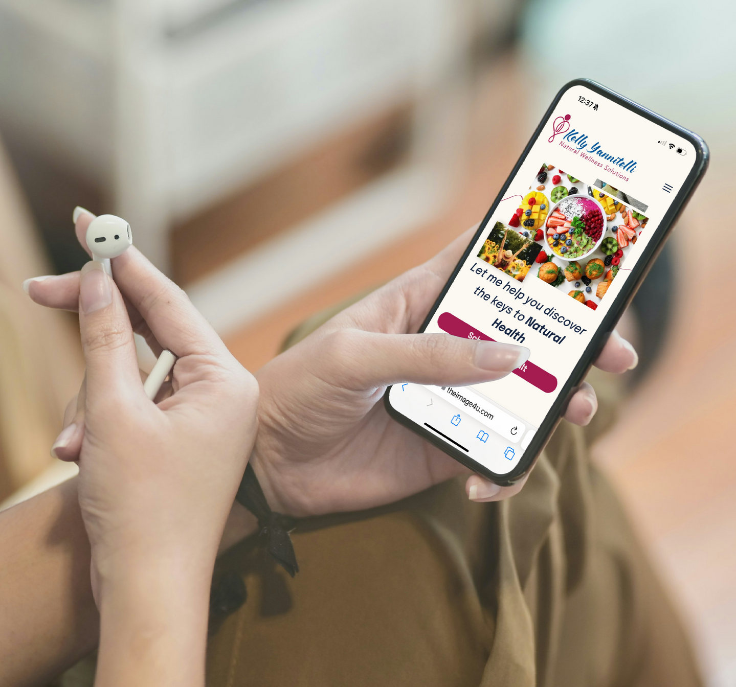 Person holding a phone with a webpage open, featuring colorful food. Earbud in other hand.