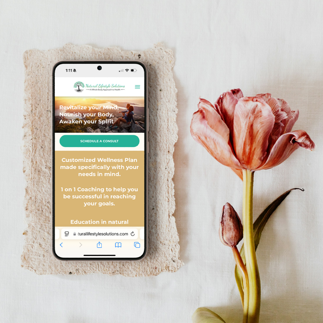 Smartphone displaying a website for wellness services, next to a pink tulip.
