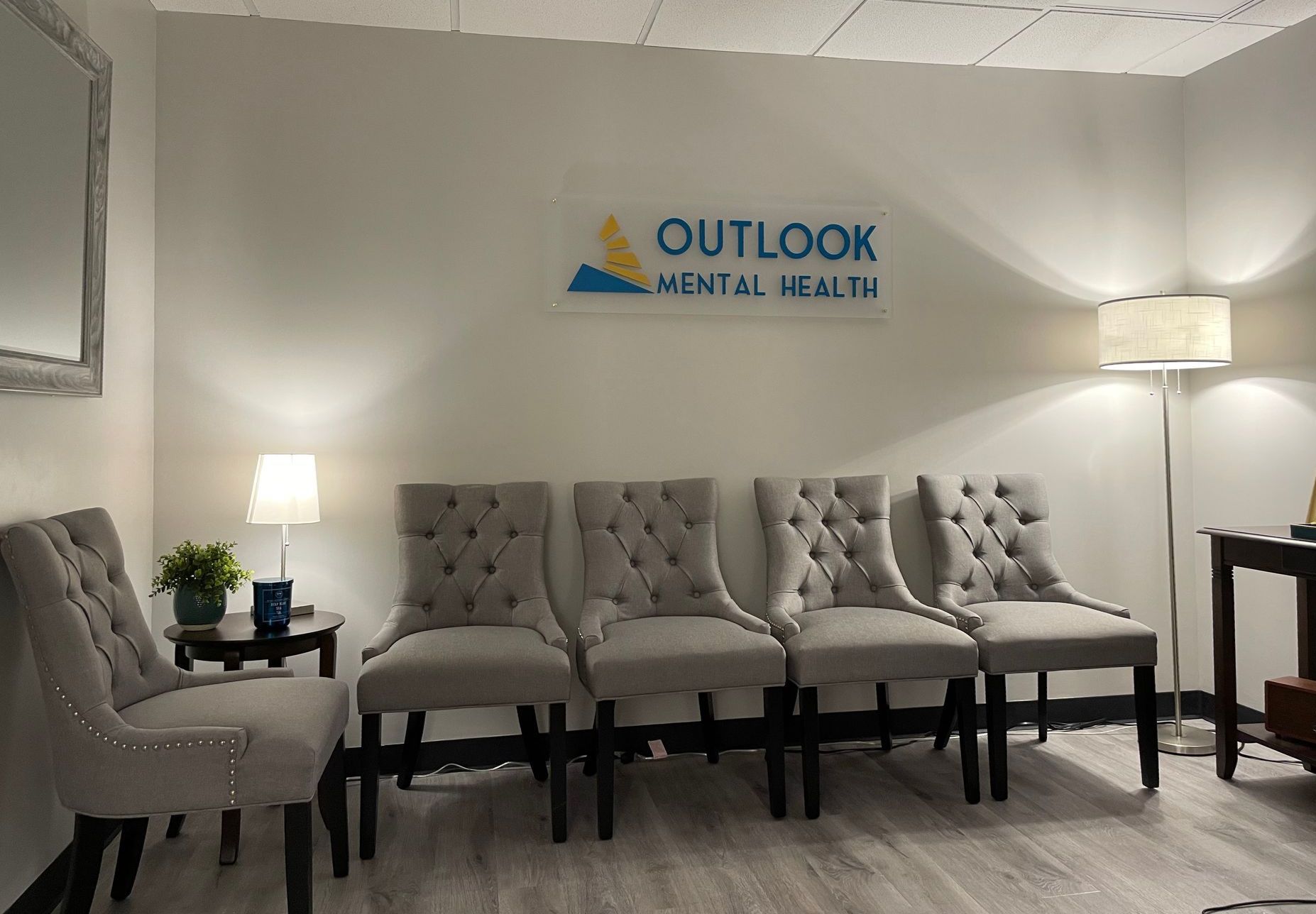 Waiting room with button-tufted chairs, lamps, and a sign that reads 