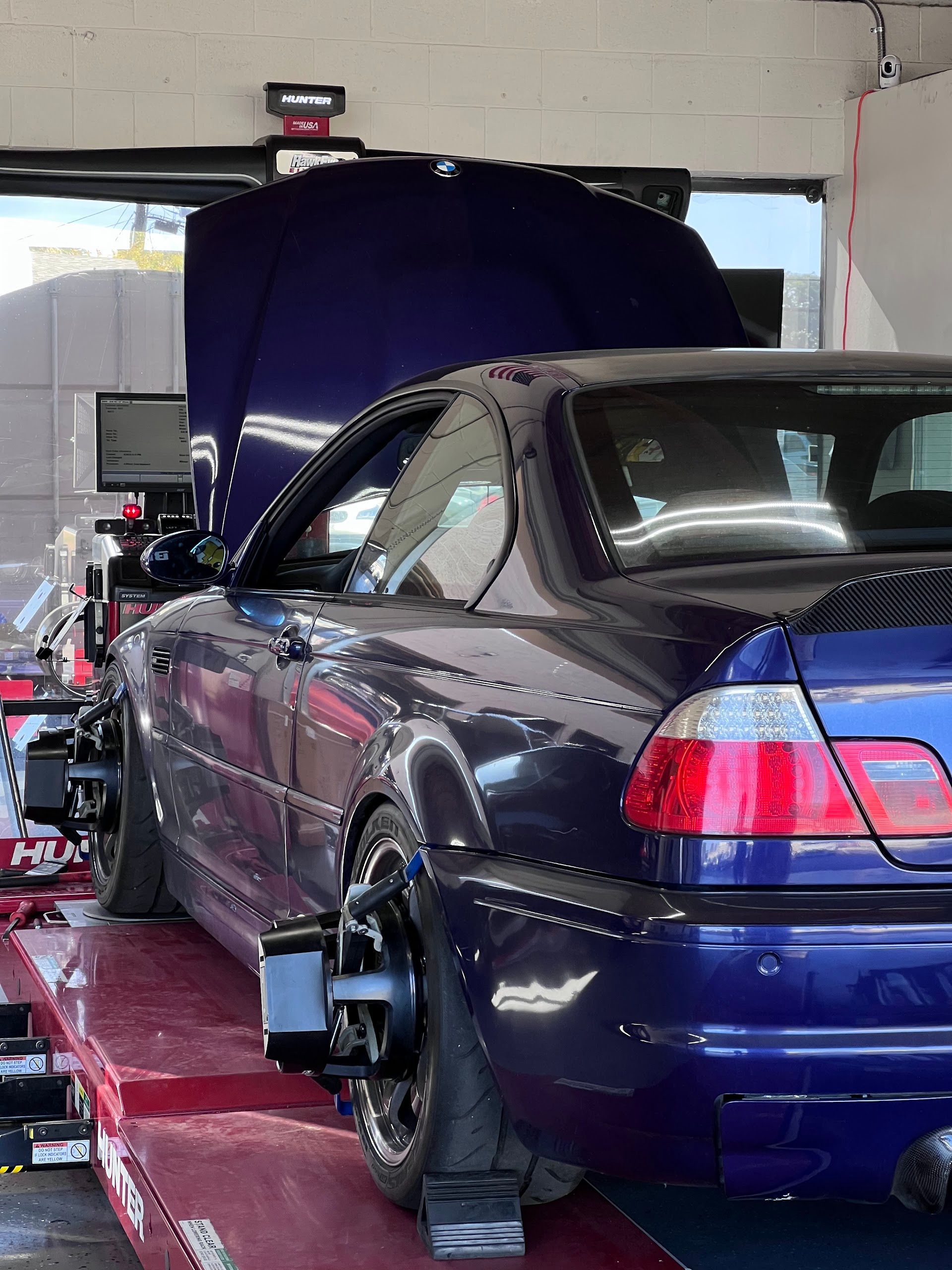 Dark blue sports coupe on a dyno with hood open in a garage | Top Alignment