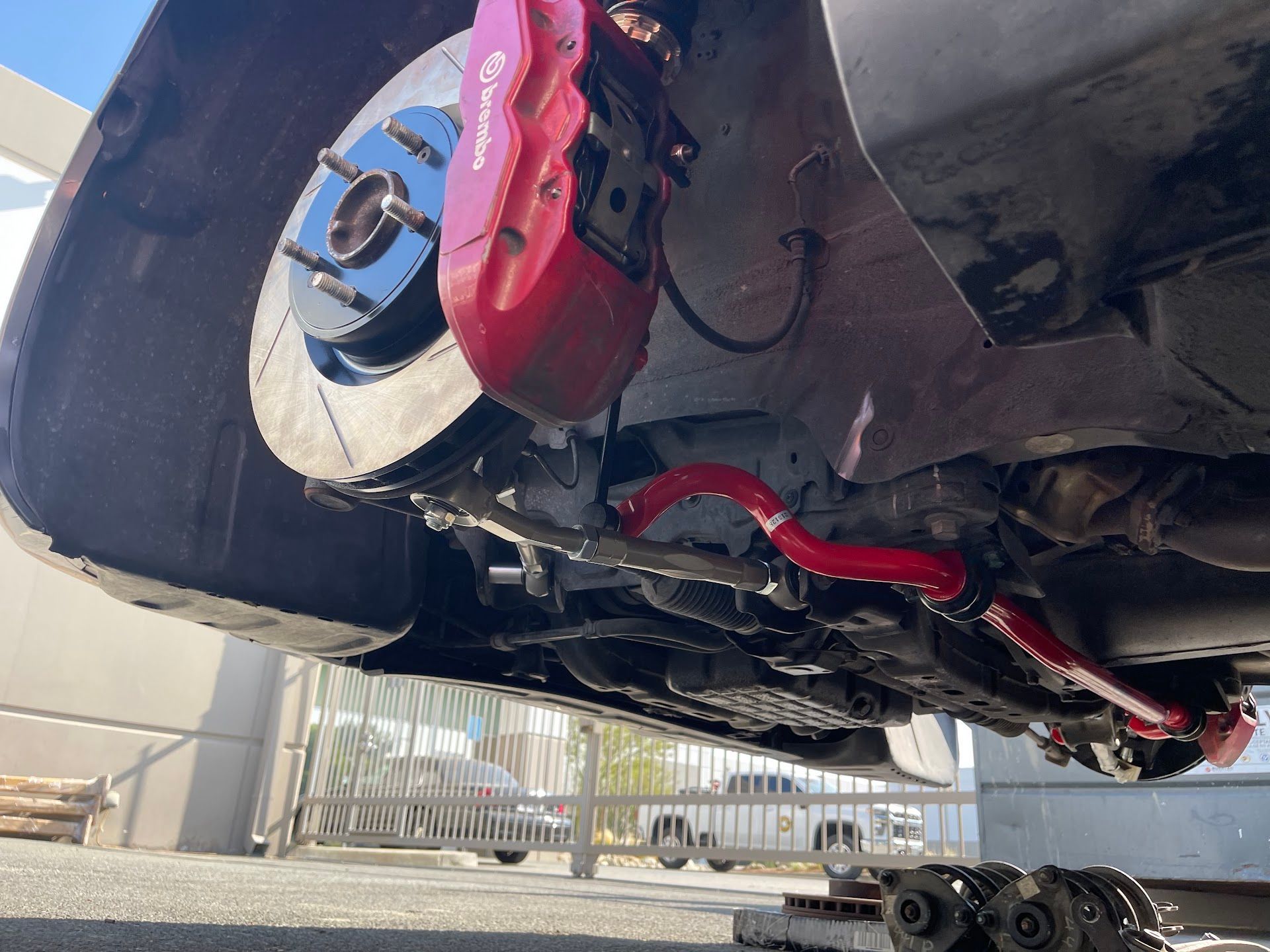 Underbody of a car on a lift, showing a red suspension component and brake assembly | Top Alignment