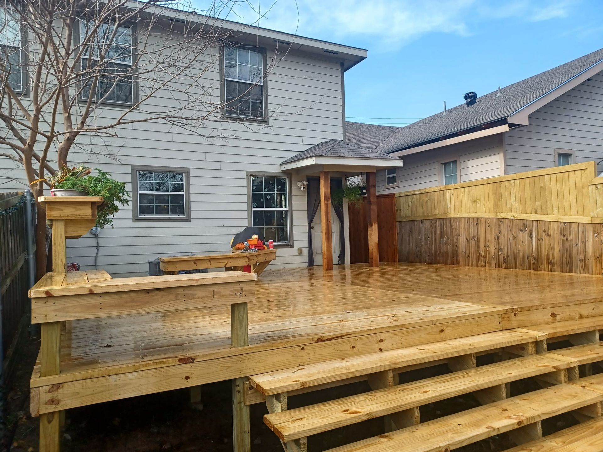 A wooden deck with stairs in front of a house. 