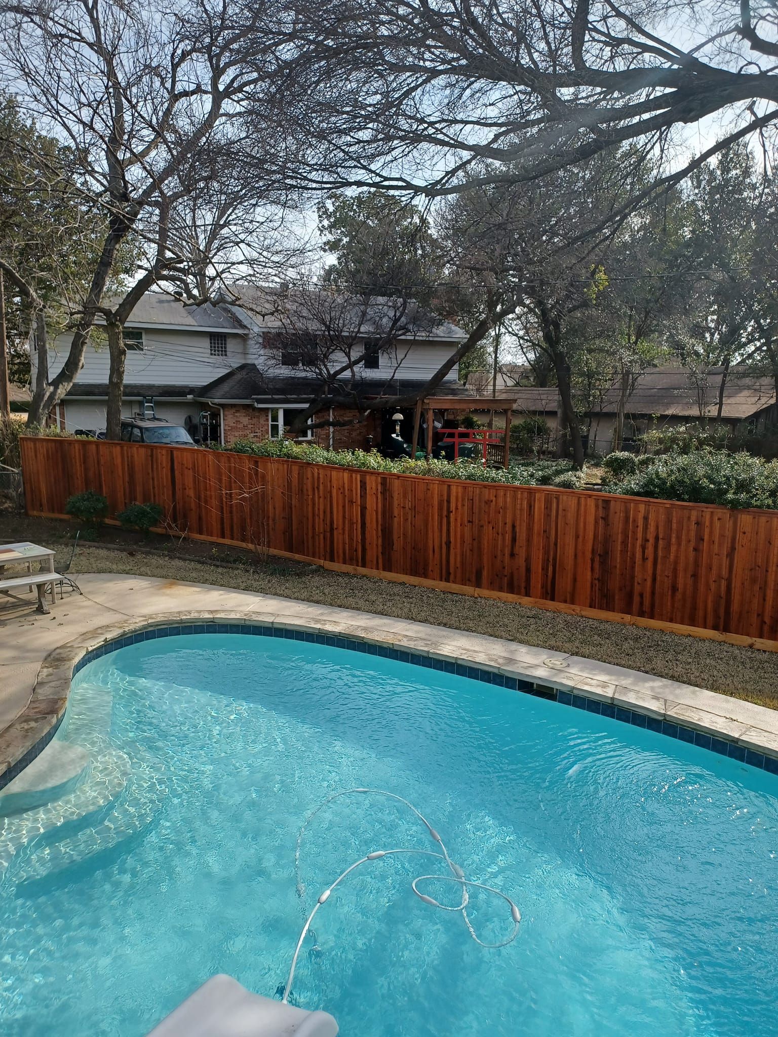 A large swimming pool with a wooden fence surrounding it.