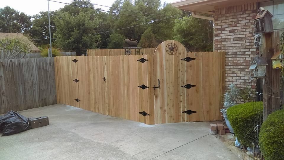 A wooden fence with a gate in front of a brick house.
