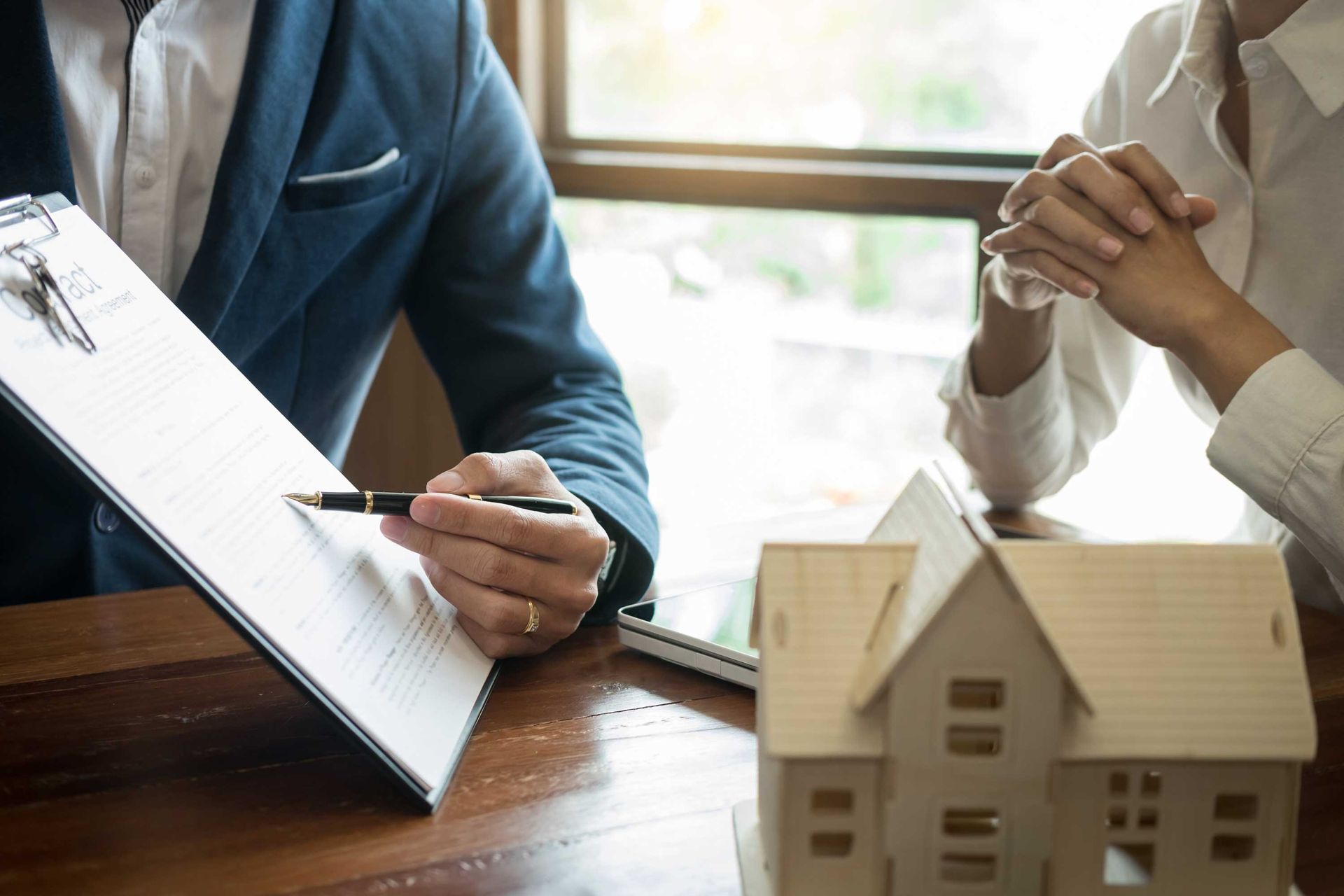 A lawyer and his client discussing a document at an office with a model home on a desk.
