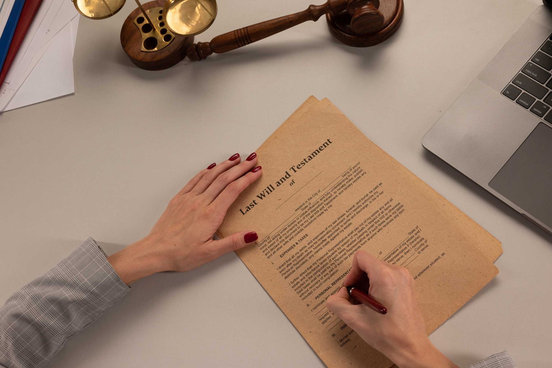 A woman signing a last will and testament document on a desk, with papers spread out around them.