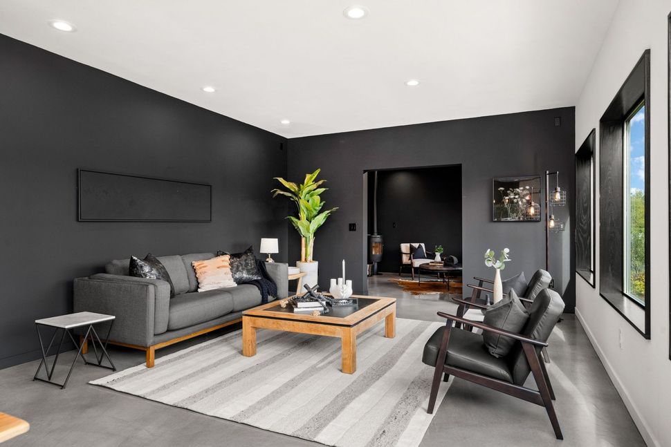 Modern gray living room with sofa, coffee table, armchairs, and large windows