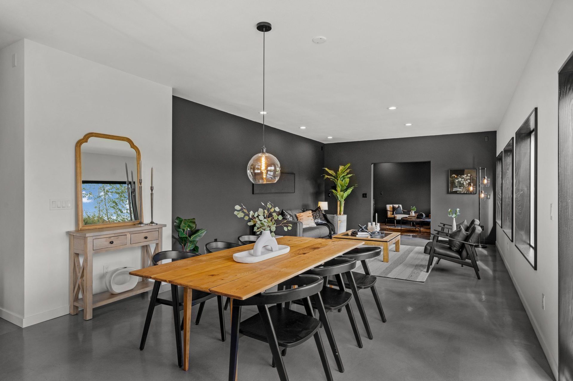 Modern dining room with wooden table, black chairs, gray walls, and a fireplace mantel