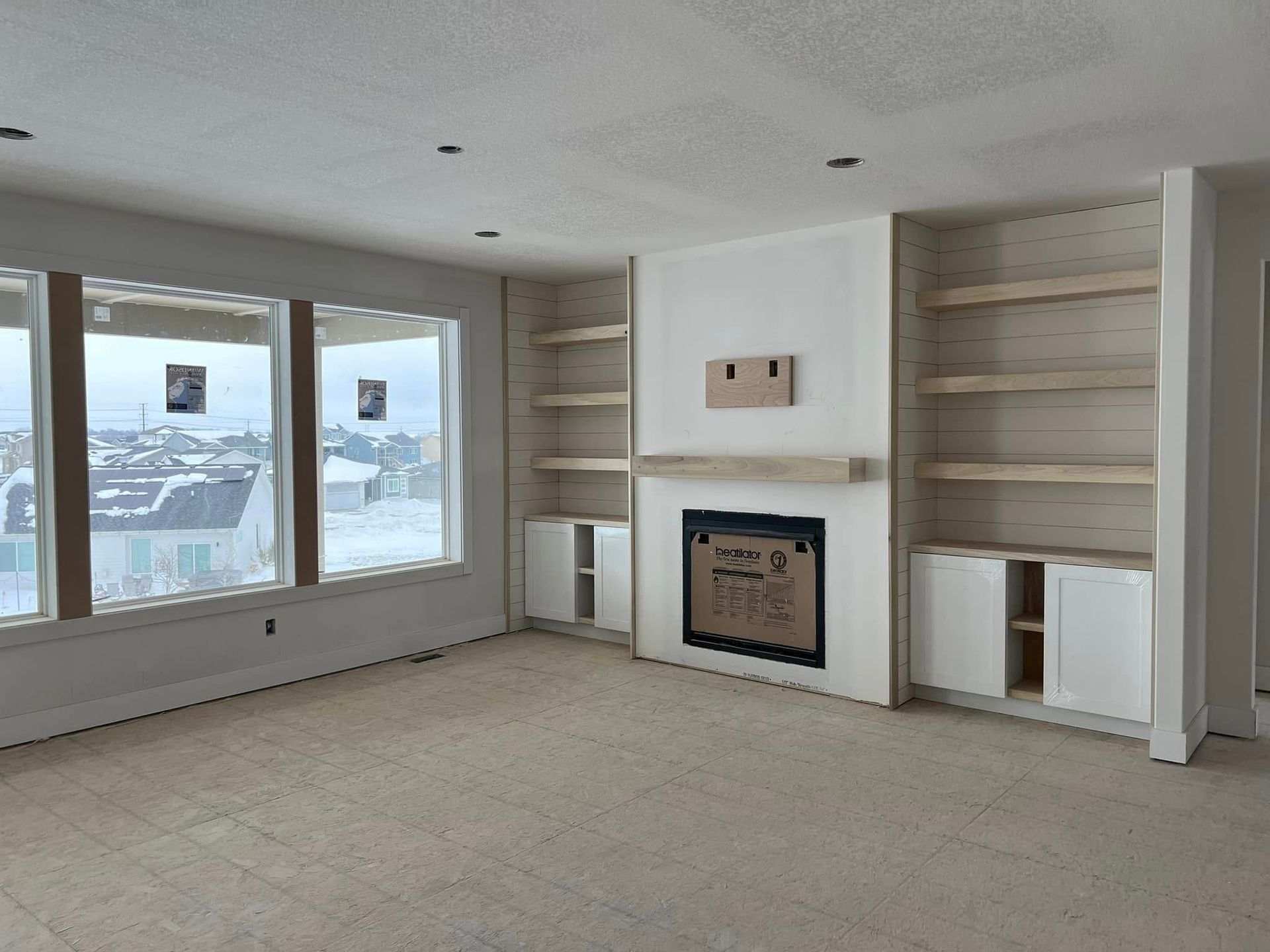An empty living room with a fireplace and shelves