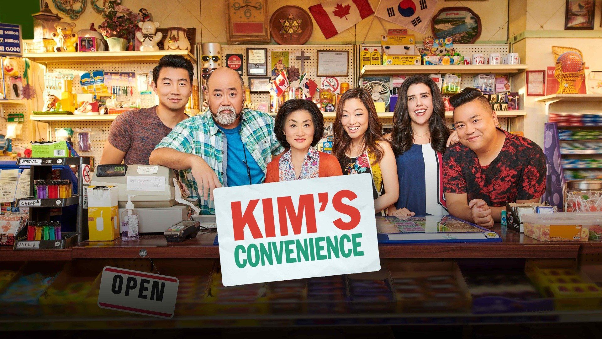Cast of the TV show Kim's Convenience behind a convenience store counter.