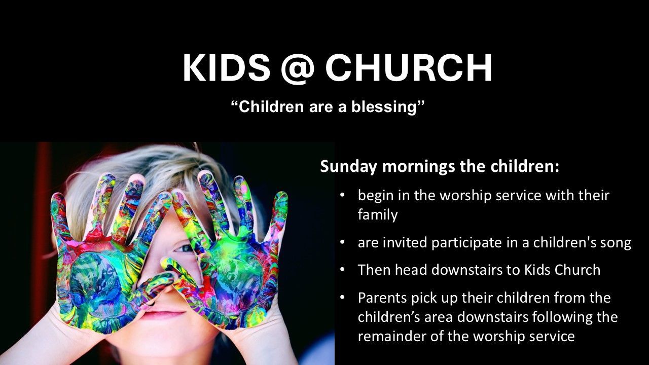 Child with hands covered in colorful paint, looking through them at the viewer.