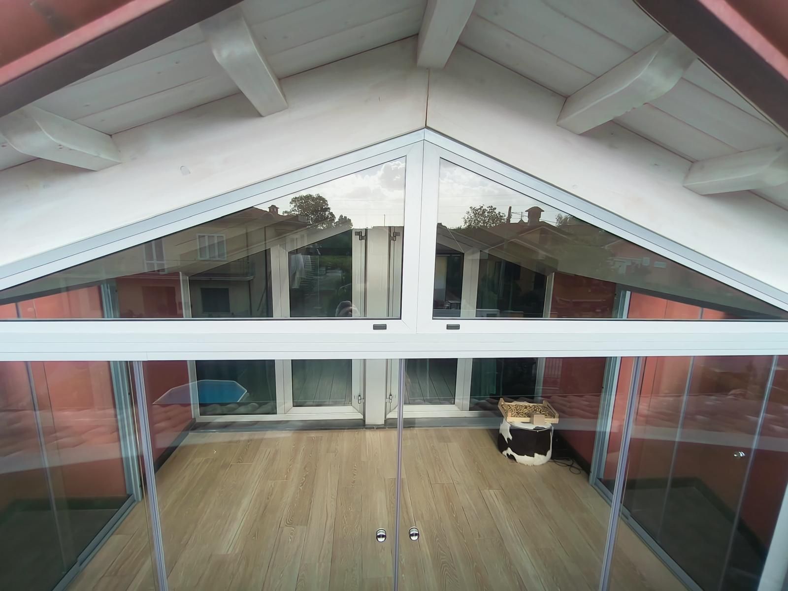 Veranda con pareti in vetro, finiture bianche e pavimento in legno