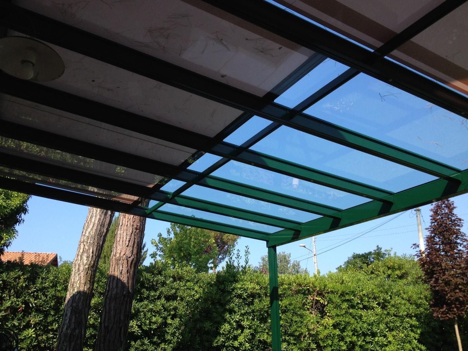 Pergola in metallo verde con pannelli blu traslucidi sopra un giardino.
