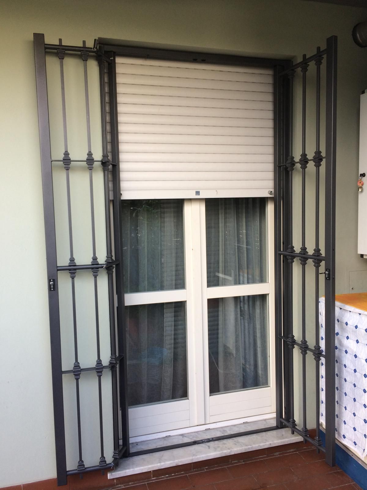 Cancelli di sicurezza in metallo si aprono accanto a una finestra con una tenda