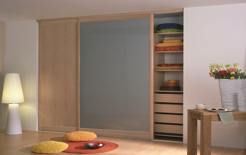 Armadio con ante scorrevoli in legno in una stanza con lampada, tappeto e tavolo.