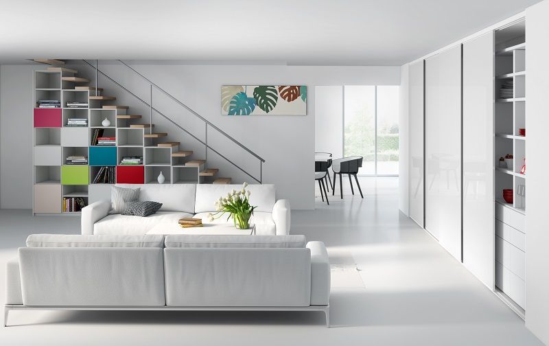 Moderno soggiorno bianco con scale e cubi contenitori colorati, divano bianco e zona pranzo aperta.