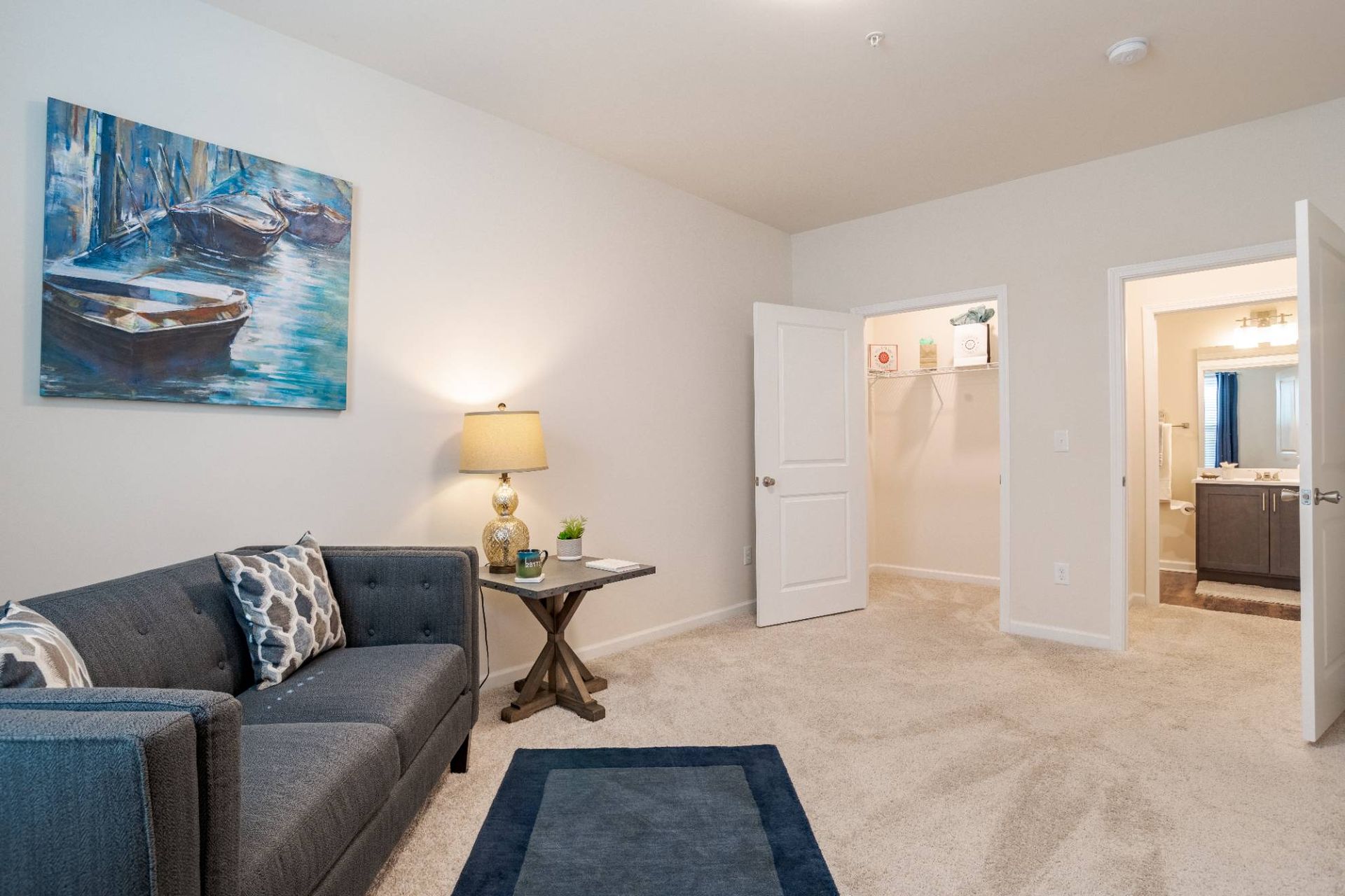Living room in an apartment with gray sofa, side table, lamp, and wall art. Contact us to learn more about our pet-friendly apartments in Waxhaw, NC, and make Waxhaw Mills your home today!