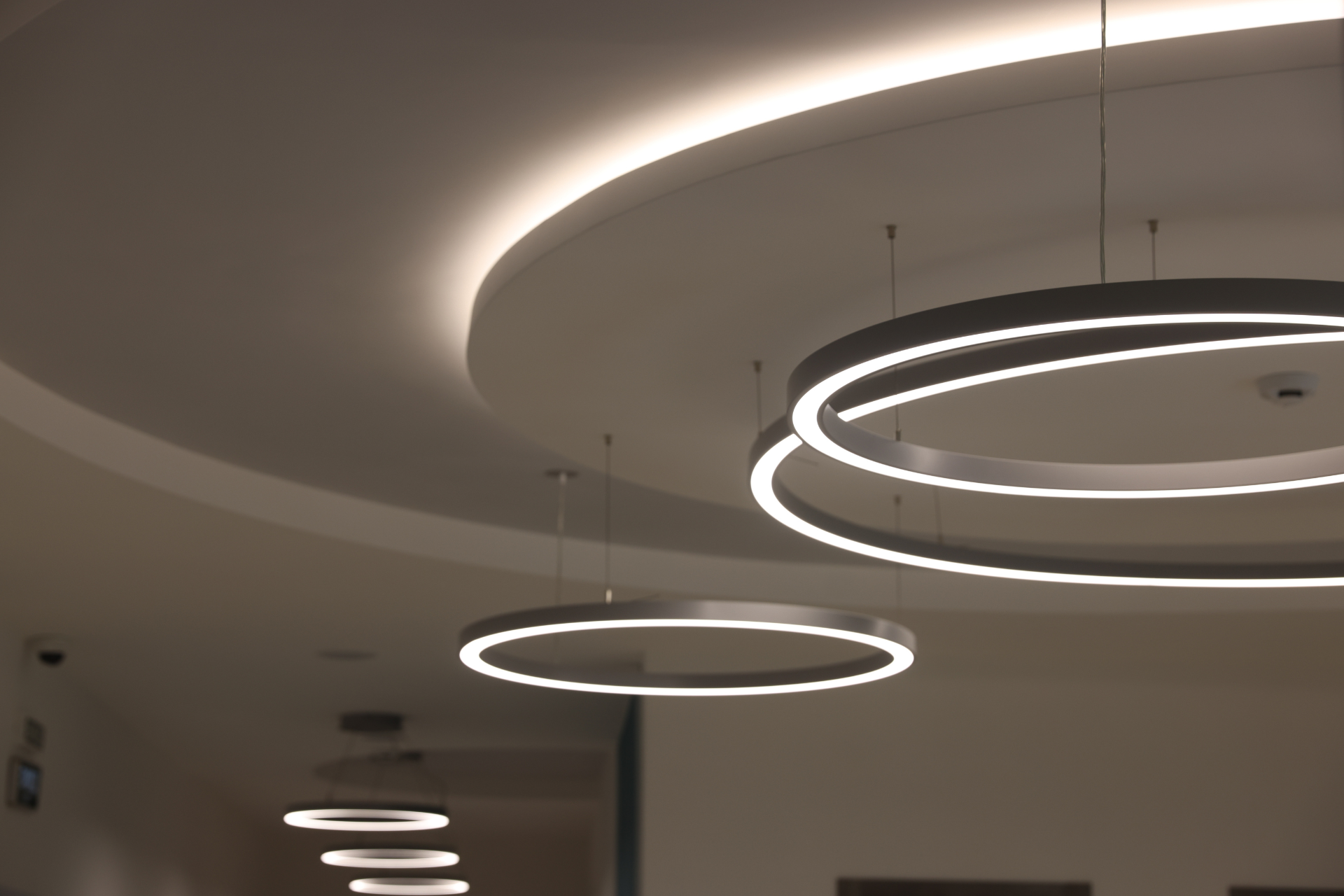 Modern ceiling with glowing circular pendant lights in a hallway or lobby