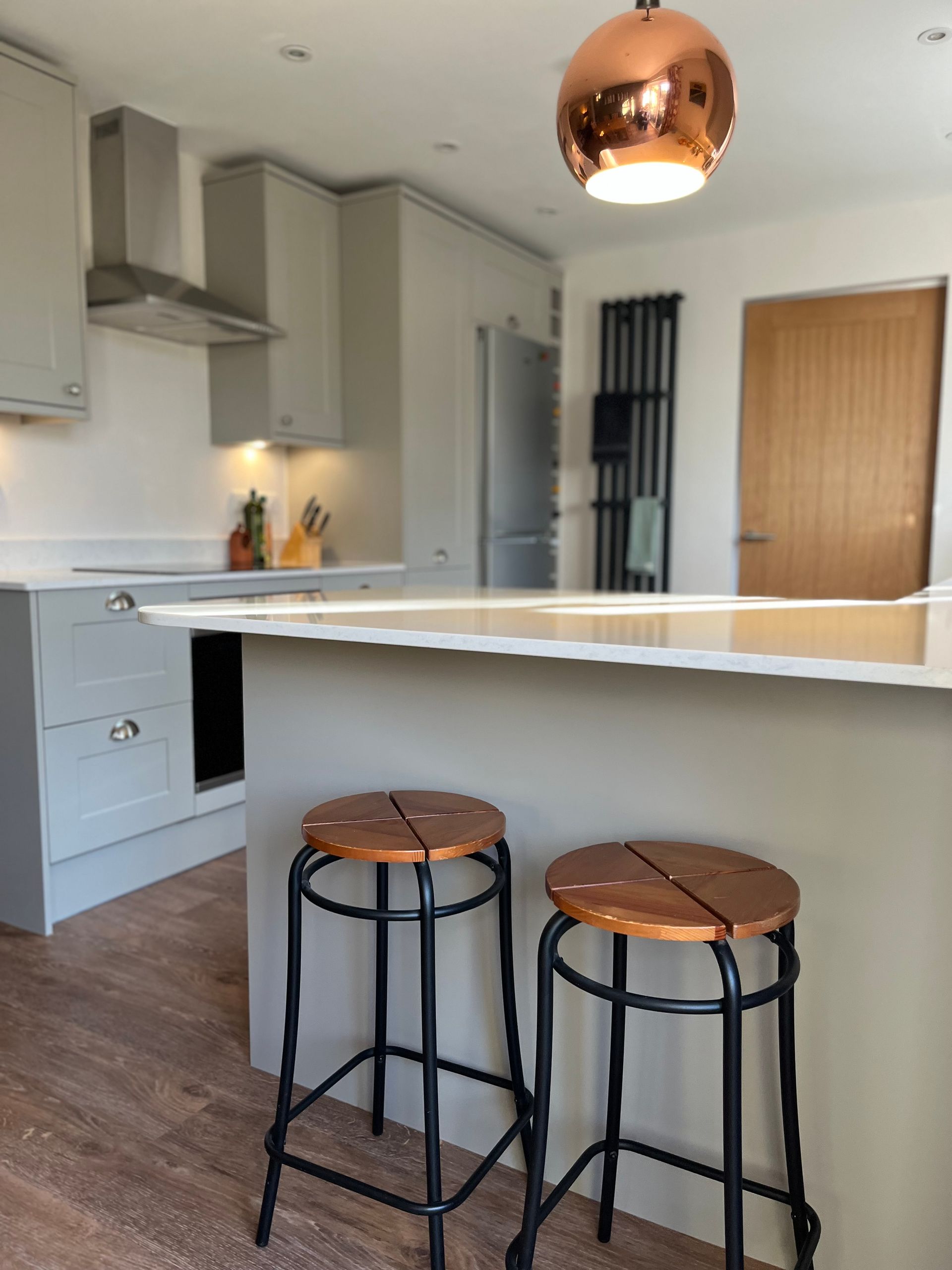 A kitchen with two copper stools and a copper pendant light