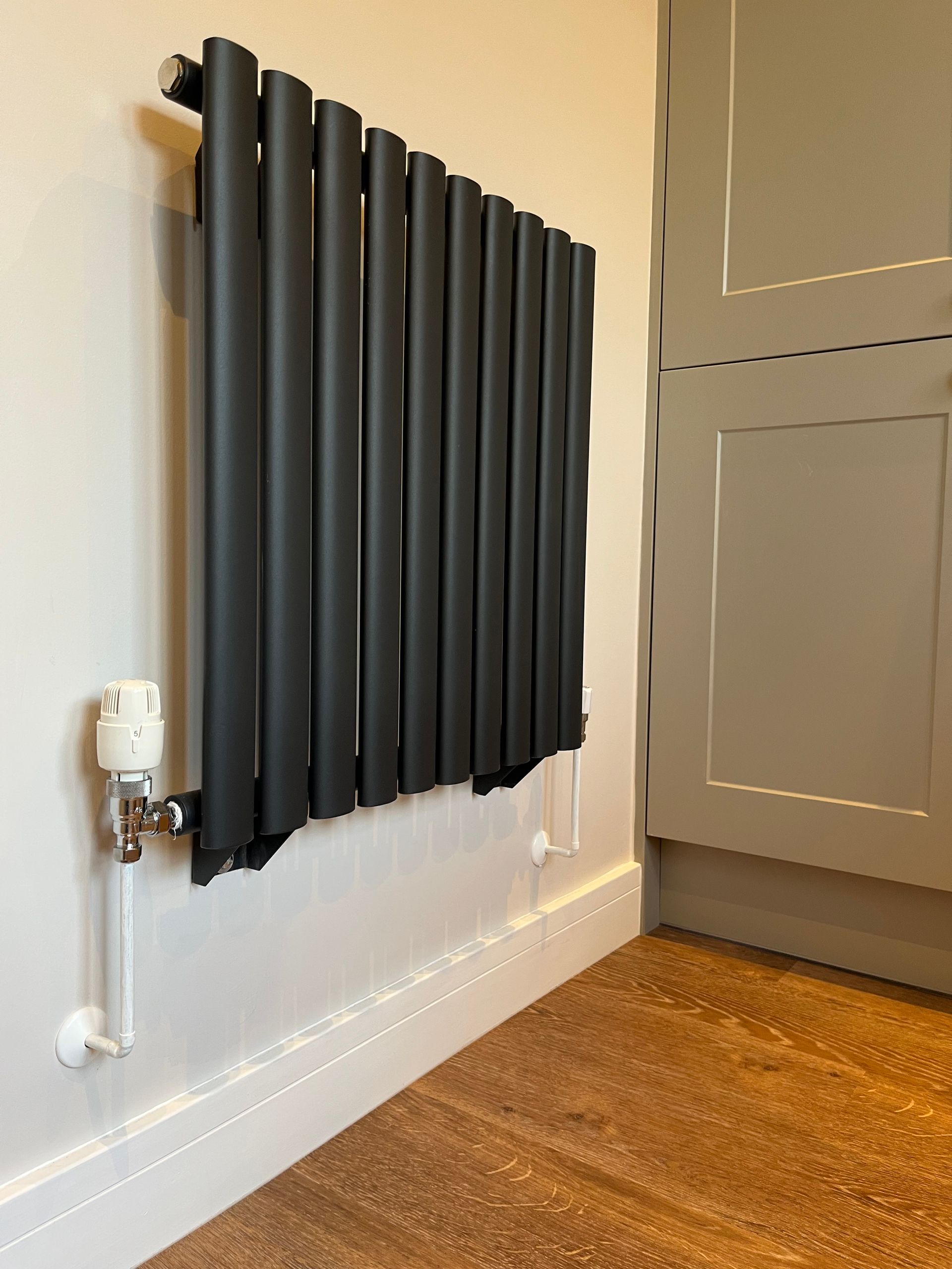 A black radiator is mounted to the wall in a room.