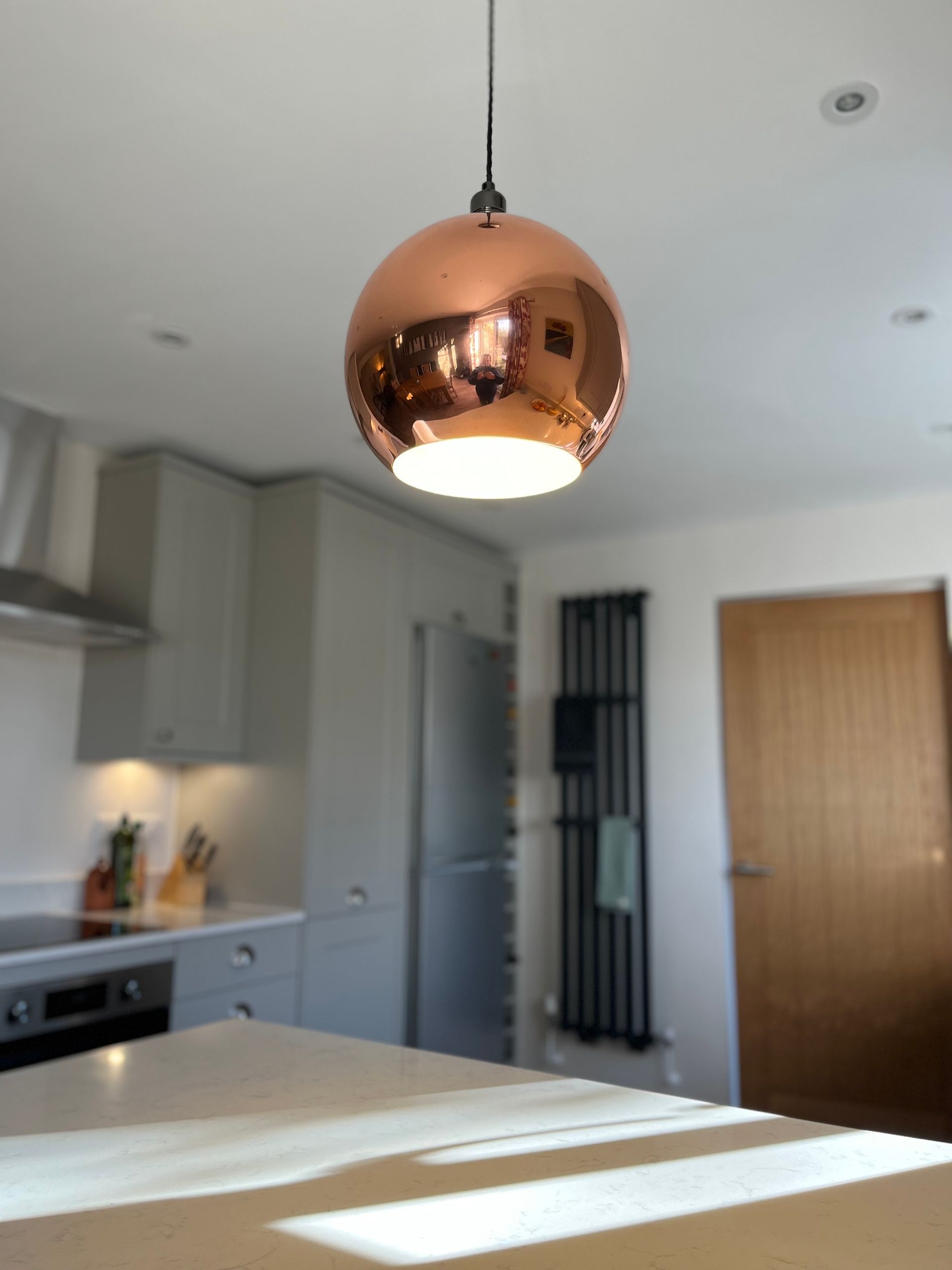 A kitchen with a copper light hanging from the ceiling