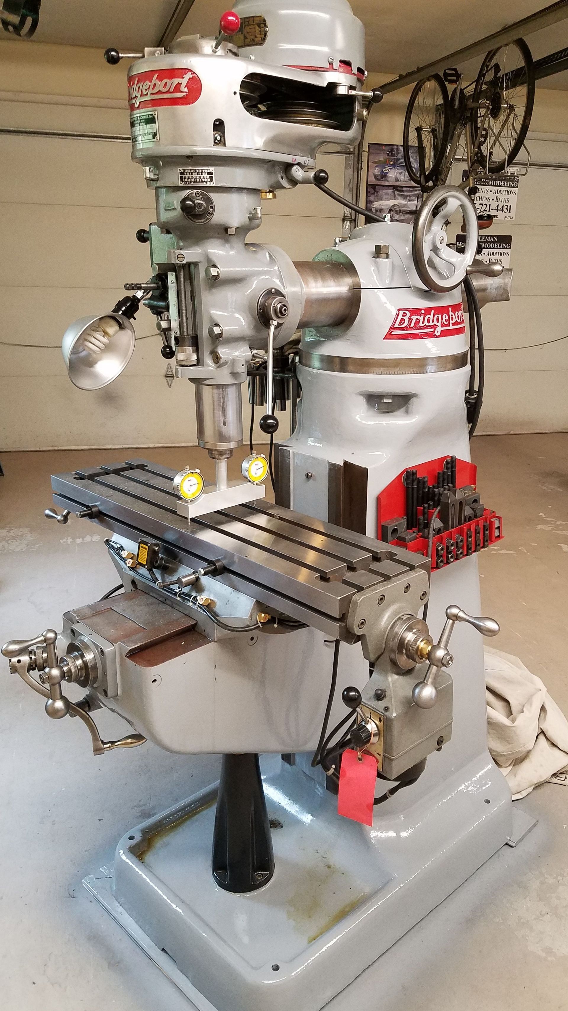 a milling machine is sitting in a garage next to a bicycle .