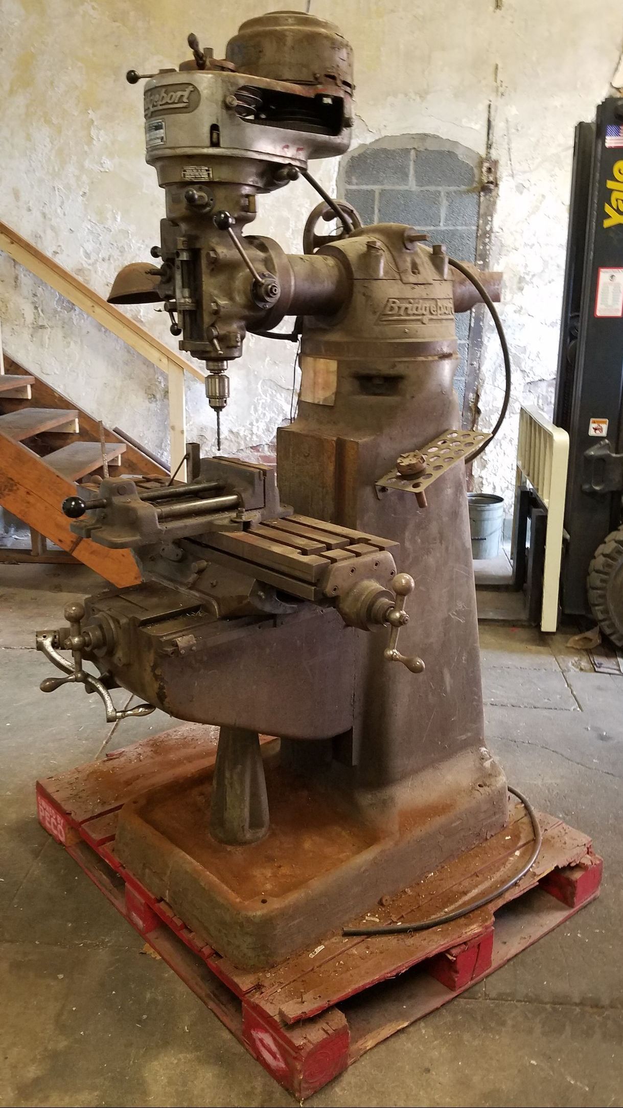 an old machine is sitting on a wooden pallet in a garage .