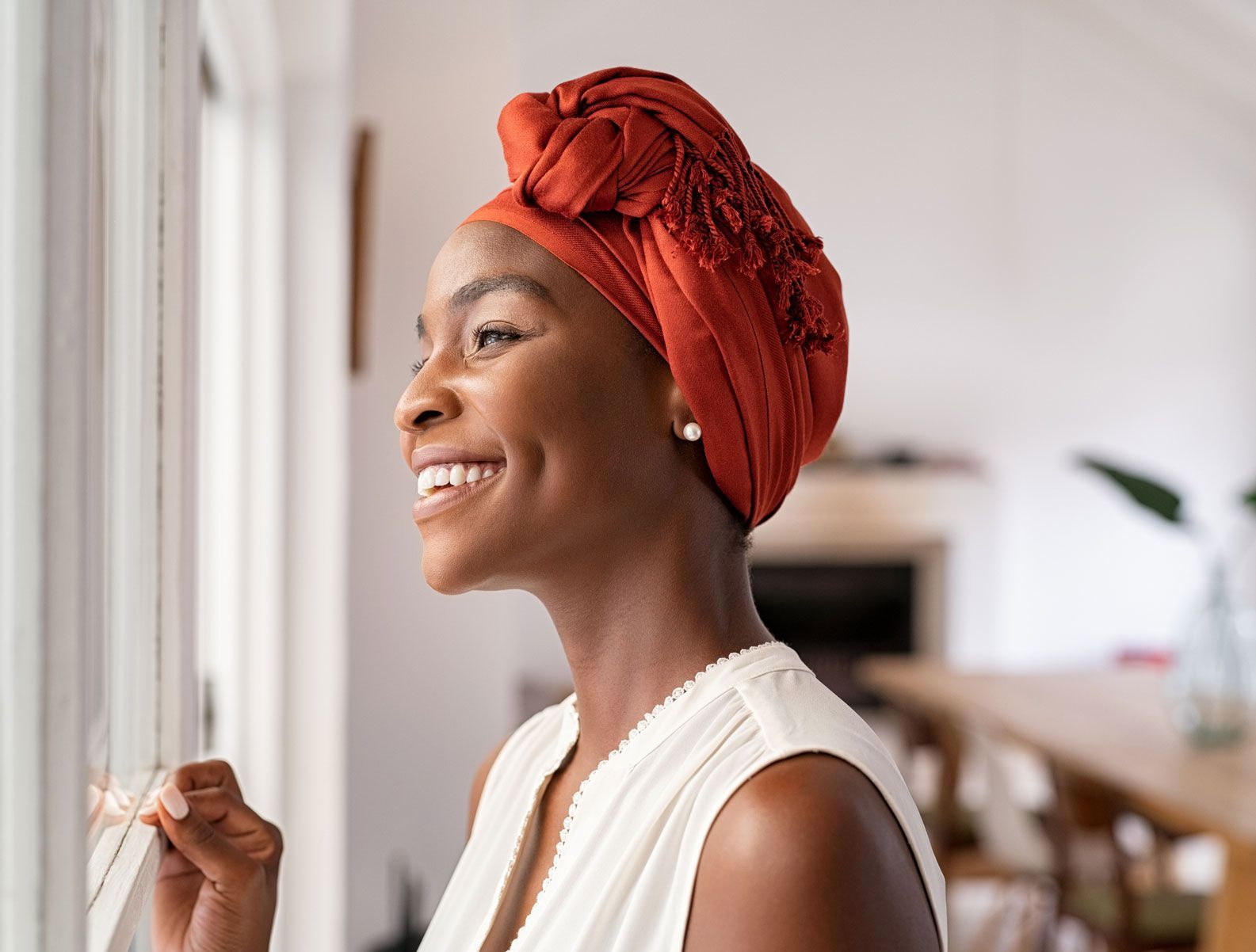 A woman wearing a head scarf is looking out of a window. A woman wearing a head scarf is looking out of a window.