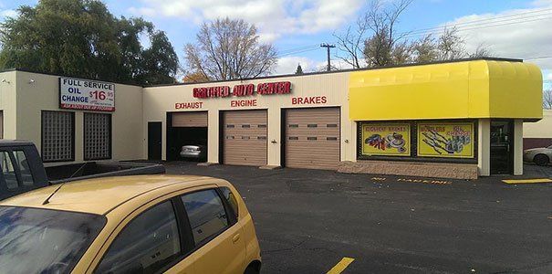 A yellow car is parked in front of a building that says metal removal