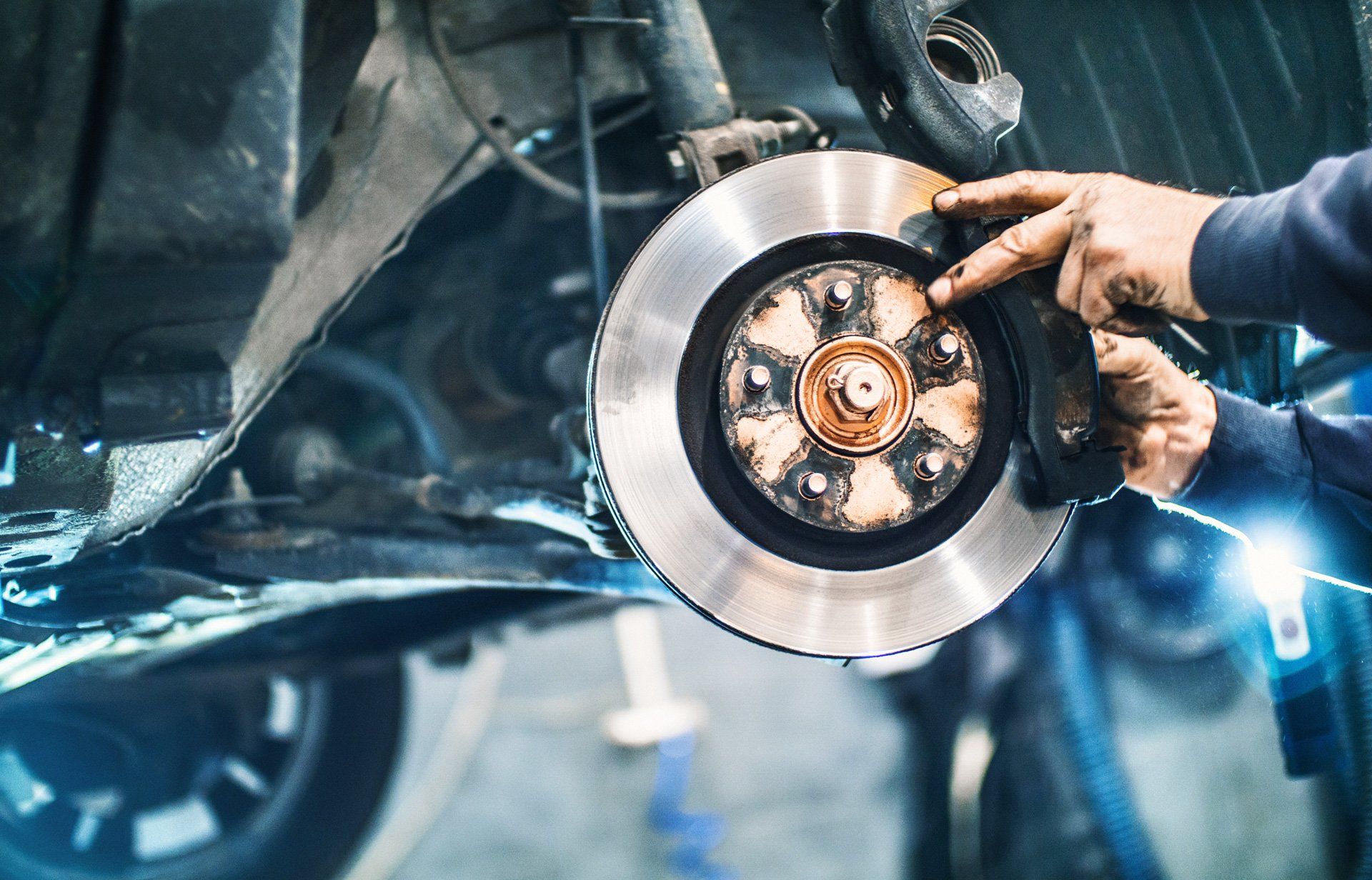 A man is fixing a brake disc on a car in a garage.