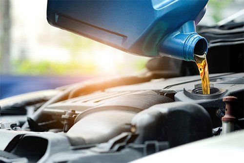 A person is pouring oil into a car engine.