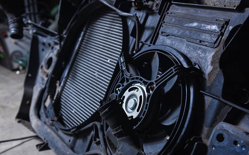 A close up of a car radiator with a fan attached to it.