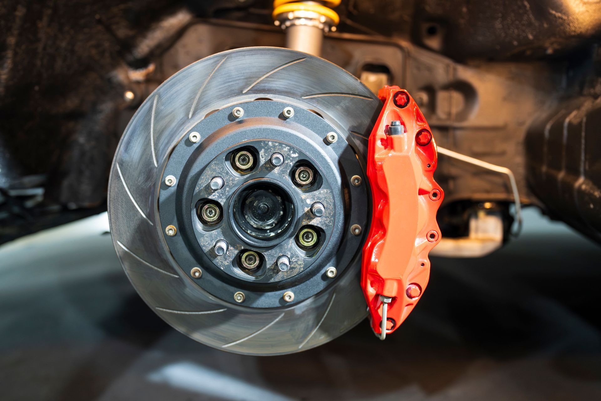 A close up of a brake disc on a car with a red brake caliper.