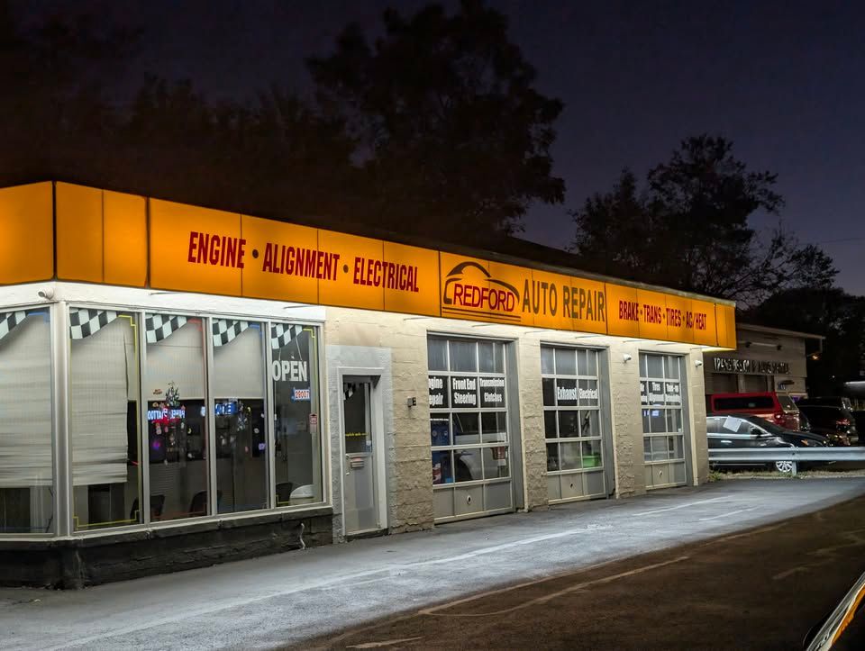 A red car is parked in front of a building that says recycling auto repair