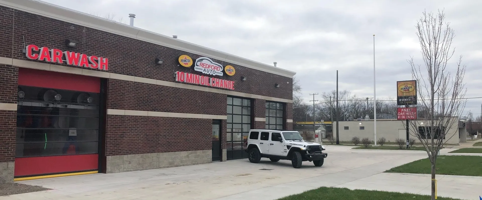 A white jeep is parked in front of a car wash.