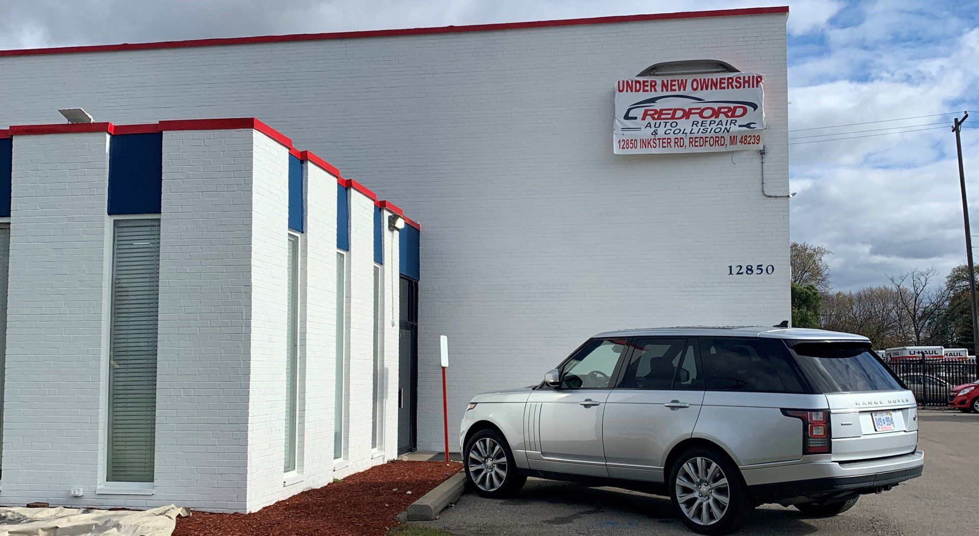 A silver range rover is parked in front of a white building.