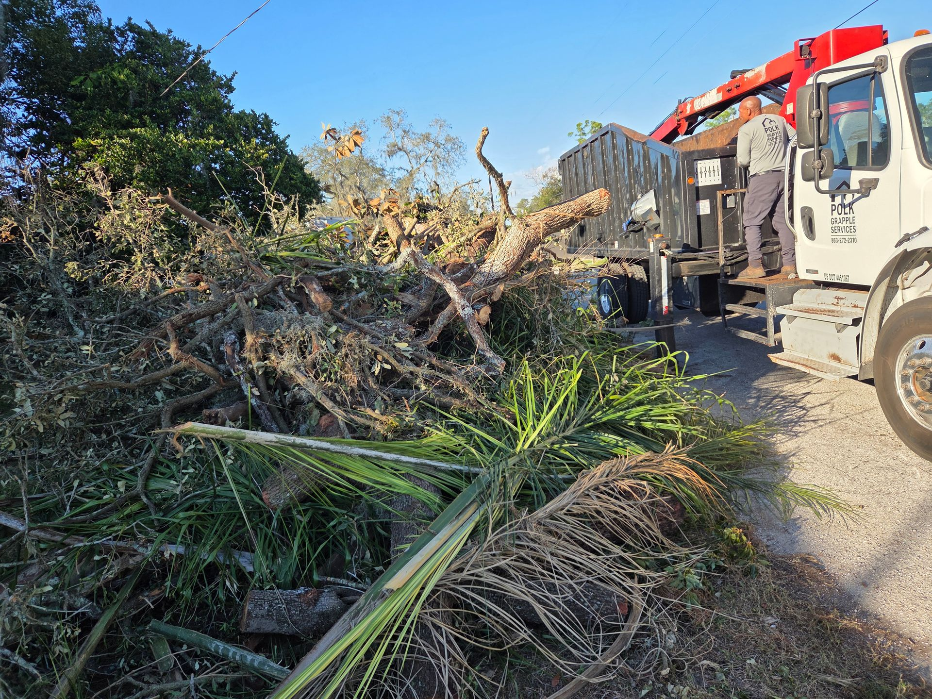 Grapple truck clearing fallen trees, large limbs, and storm debris from a property in Polk County, Florida.