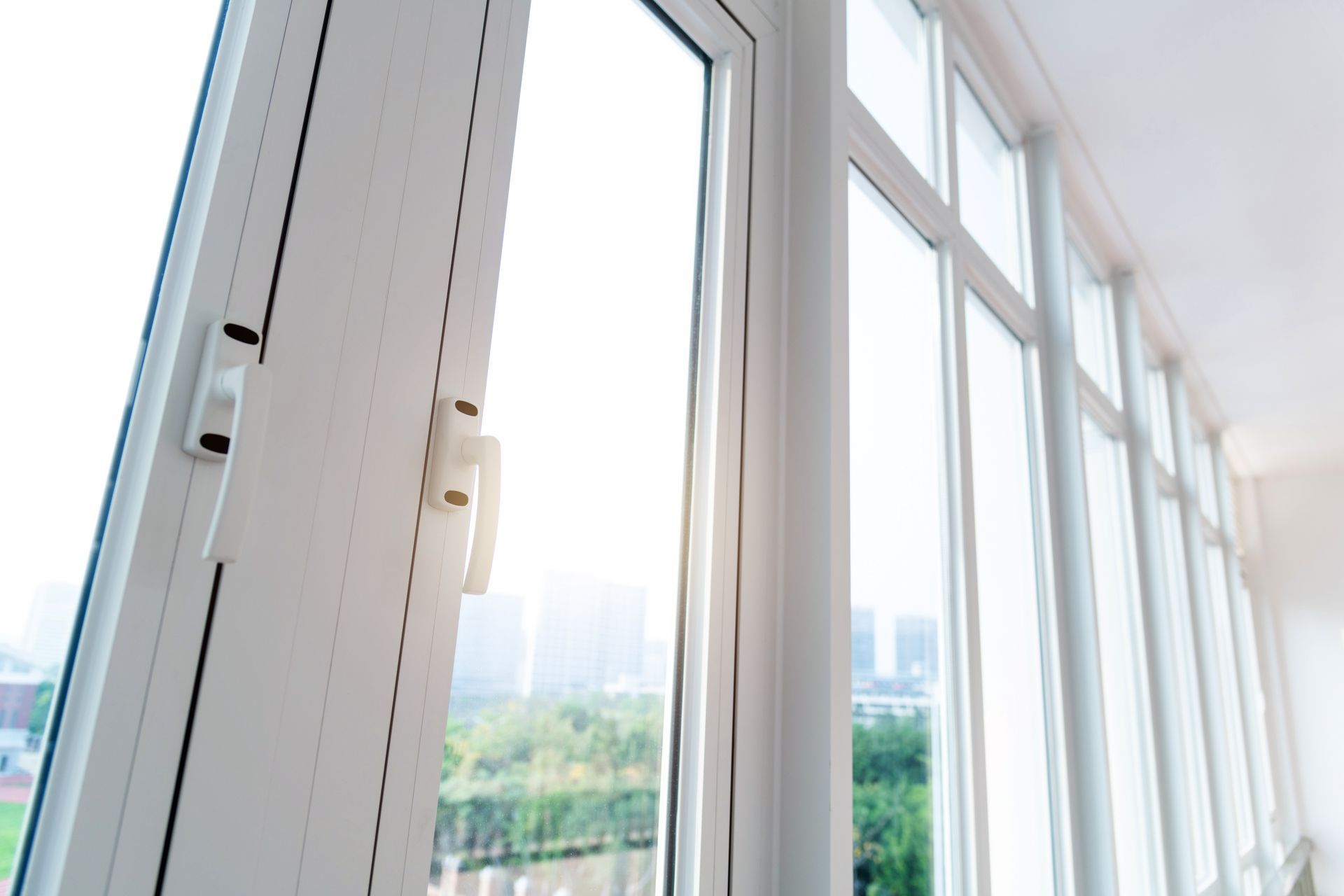 Open white window with a view of a city through the glass, bright natural light. Open white window with a view of a city through the glass, bright natural light.