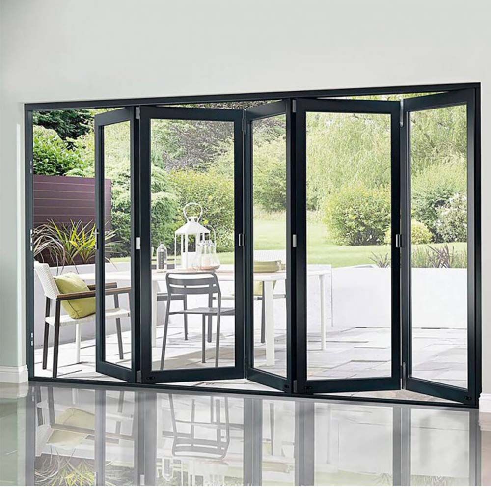 Folding glass doors open to a patio with outdoor furniture, trees, and greenery. Folding glass doors open to a patio with outdoor furniture, trees, and greenery.