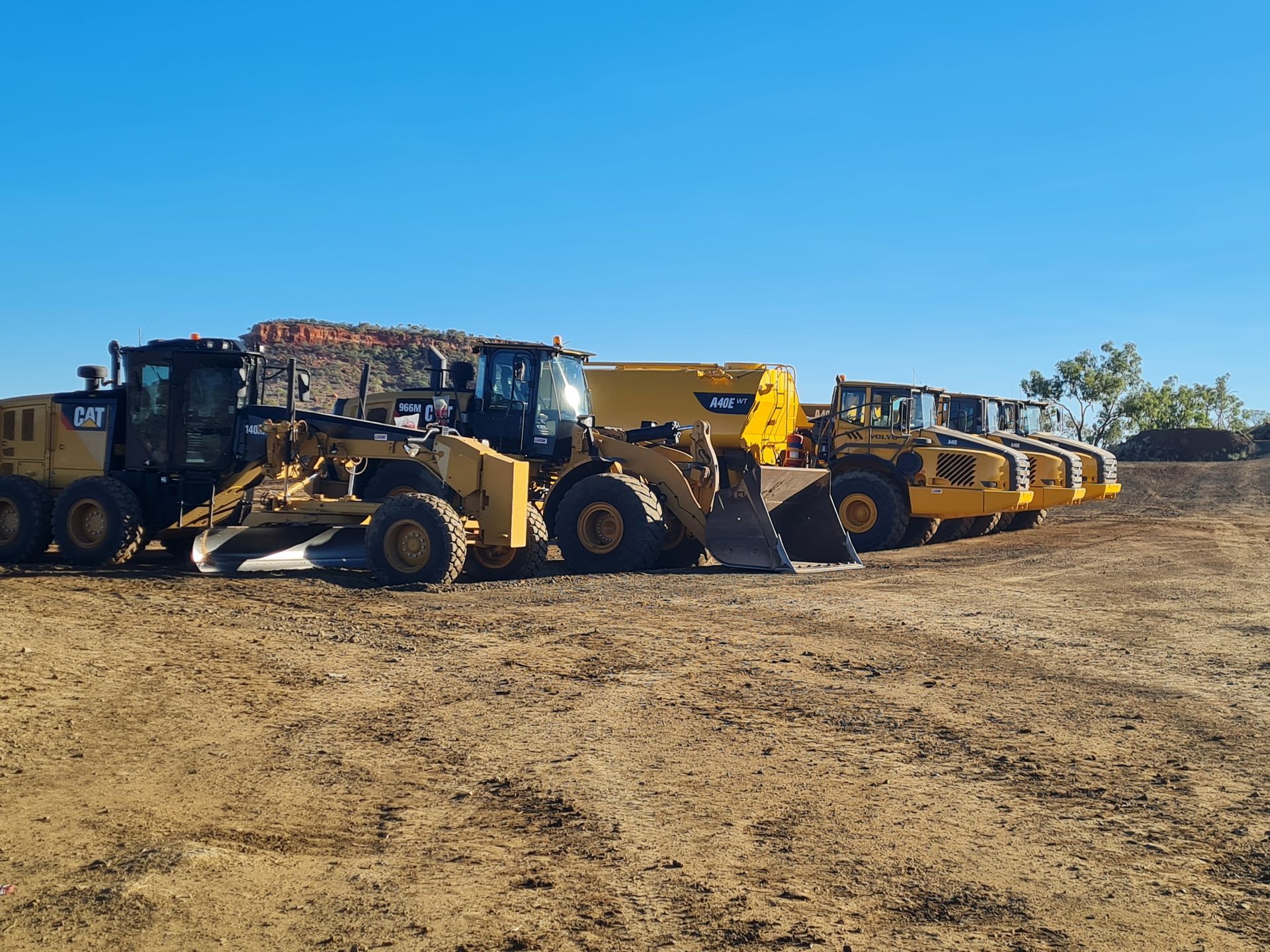 Yellow construction vehicles parked on dirt under a clear blue sky.— Lamont Civil Services Pty Ltd In Townview, QLD