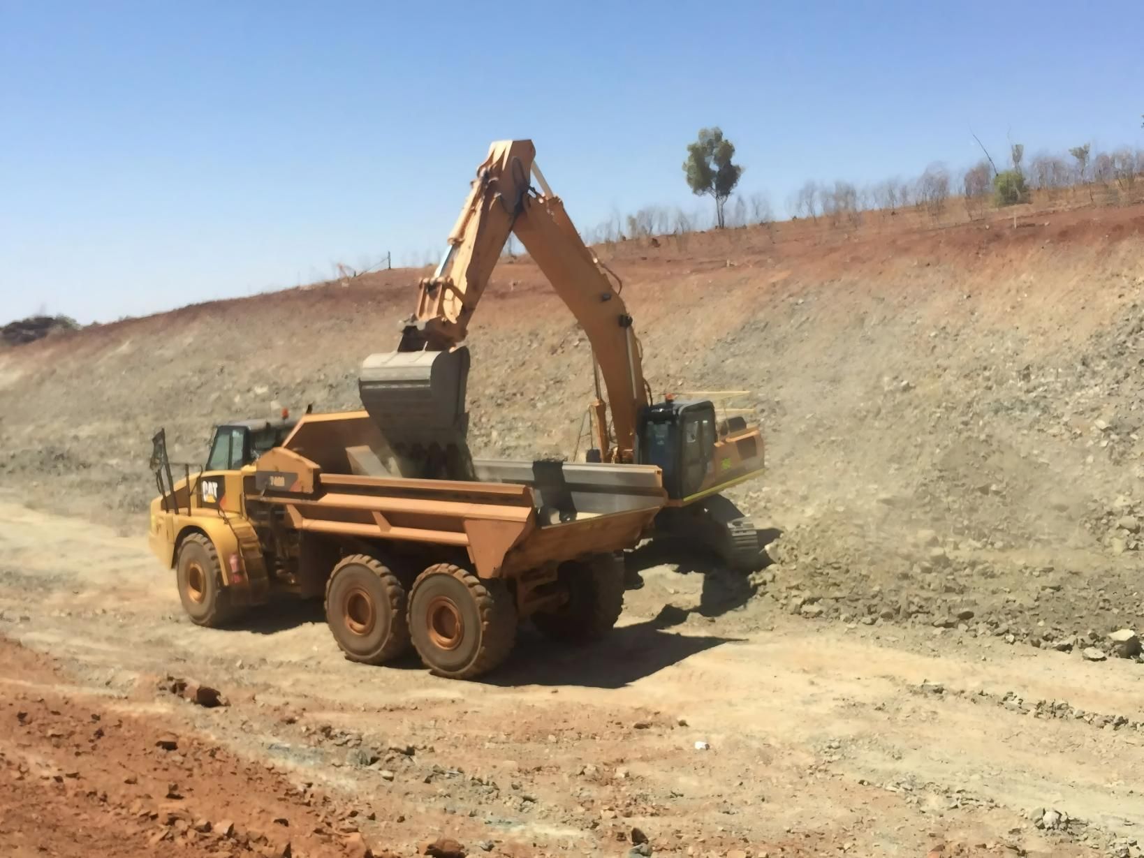 An Excavator Loading a Yellow Dump Truck With Dirt on a Construction Site — Lamont Civil Services Pty Ltd In Townview, QLD