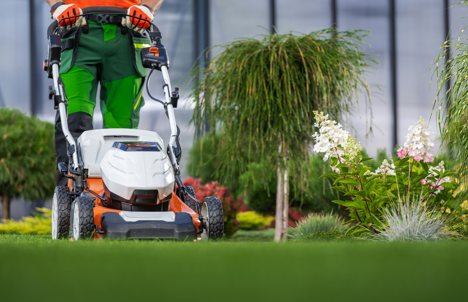Person mowing a green lawn with an orange and white lawnmower Person mowing a green lawn with an orange and white lawnmower
