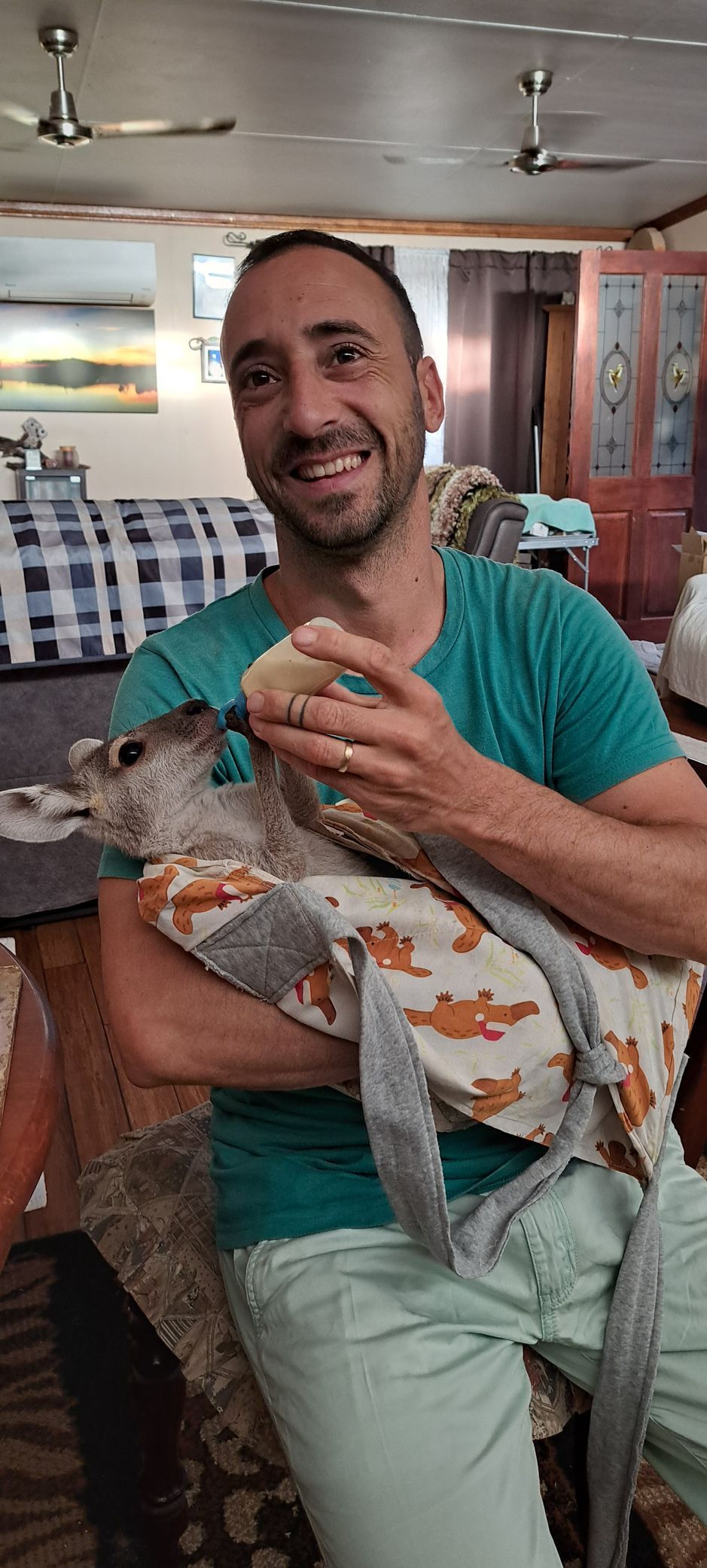 A man is holding a cat in his arms in a living room.