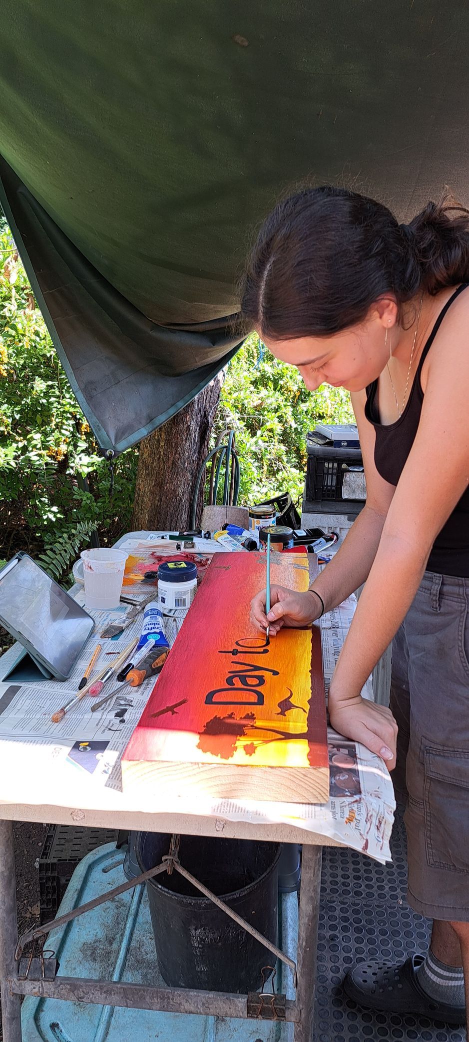 A woman is sitting at a table painting a picture.